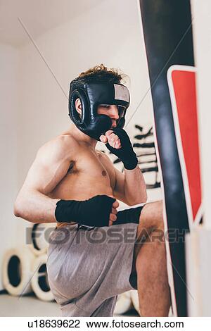 Man wearing head protector sparring with punchbag View Large Photo Image Stock Image - Man wearing head protector sparring with punchbag. Fotosearch