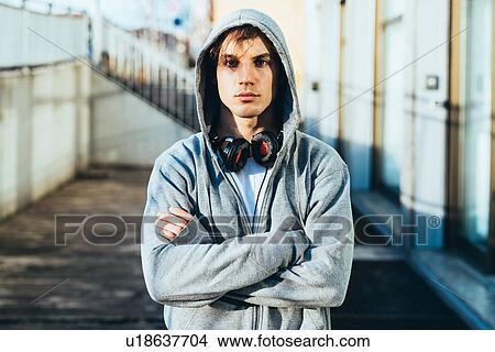 Man wearing hooded top and headphones, arms crossed looking at camera View Large Photo Image Picture - Man wearing hooded top and headphones, arms crossed looking at camera. Fotosearch