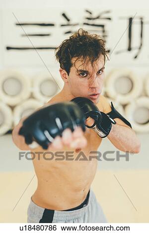 Man wearing kickboxing gloves in sparring stance looking at camera View Large Photo Image Stock Photograph - Man wearing kickboxing gloves in sparring stance looking at camera. Fotosearch