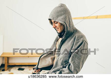 Man zipping up hooded top looking down smiling View Large Photo Image Stock Photography - Man zipping up hooded top looking down smiling. Fotosearch