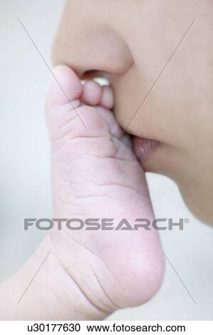 Stock Image - Mother kissing her newborn's foot. Fotosearch