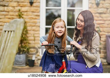 Mother teaching daughter to rise bicycle View Large Photo Image Stock Photo - Mother teaching daughter to rise bicycle. Fotosearch