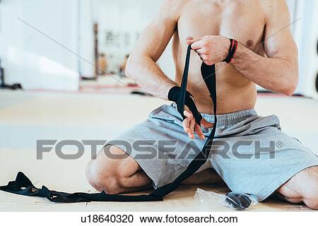 Stock Image - Neck down of man kneeling wrapping hands. Fotosearch