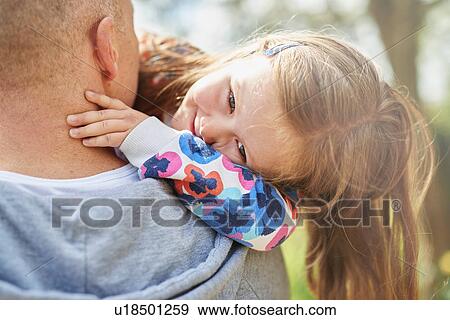 Over shoulder view of father carrying smiling daughter View Large Photo Image Stock Photo - Over shoulder view of father carrying smiling daughter. Fotosearch