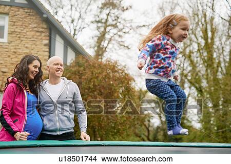 Parents watching daughter bounce on trampoline View Large Photo Image Picture - Parents watching daughter bounce on trampoline. Fotosearch