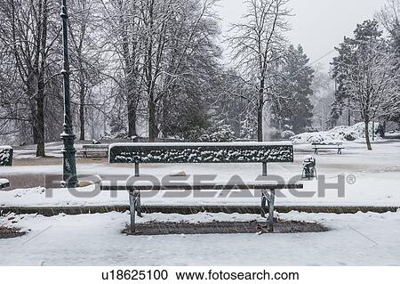 Stock Image - Park bench in snow covered park. Fotosearch