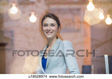 Picture - Portrait of businesswoman looking through office window. Fotosearch