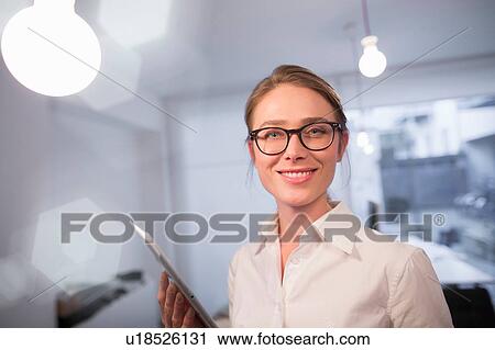 Stock Image - Portrait of businesswoman using digital tablet in office. Fotosearch