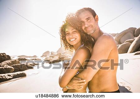 Stock Photograph - Portrait of couple hugging on beach, Cape Town, South Africa. Fotosearch