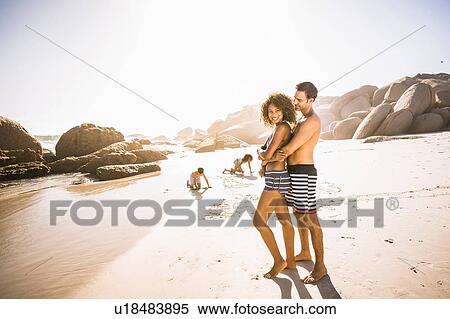 Stock Photography - Portrait of couple with two children hugging on beach, Cape Town, South Africa. Fotosearch