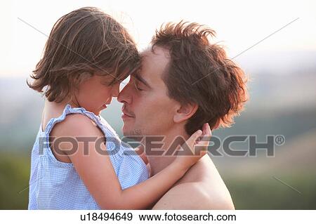 Stock Photo - Portrait of man and daughter face to face with eyes closed, Buonconvento, Tuscany, Italy. Fotosearch