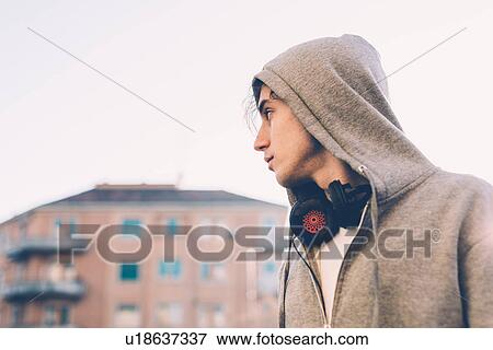 Stock Photo - Portrait of man wearing hooded top and headphones looking away. Fotosearch
