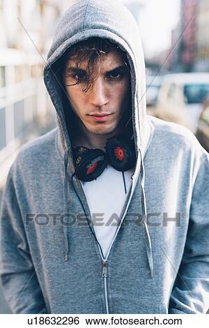 Stock Photograph - Portrait of man wearing hooded top and headphones looking at camera. Fotosearch