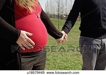 Pregnant couple walking in park View Large Photo Image Stock Photo - Pregnant couple walking in park. Fotosearch