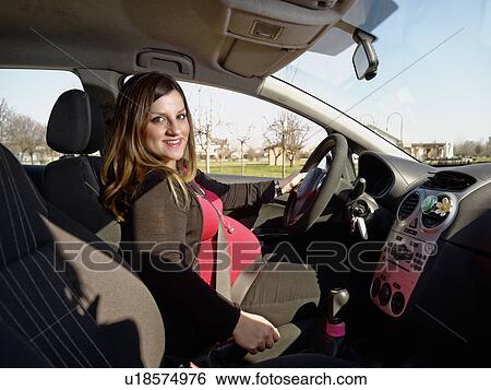 Stock Photograph - Pregnant woman behind wheel of vehicle. Fotosearch