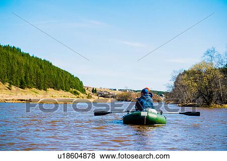 Stock Photo - Rear view of couple rowing on river in dinghy. Fotosearch