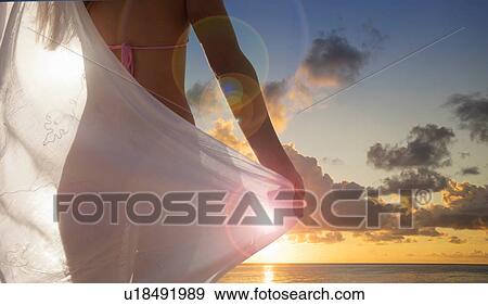 Stock Photo - Rear view of young woman with scarf watching sunset on Miami Beach, Florida, USA. Fotosearch
