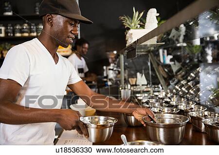 Stock Image - Restaurant worker arranging bowls in display cabinet. Fotosearch