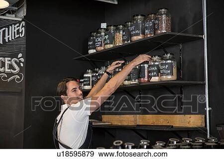 Stock Photo - Restaurateur arranging jars on shelf. Fotosearch