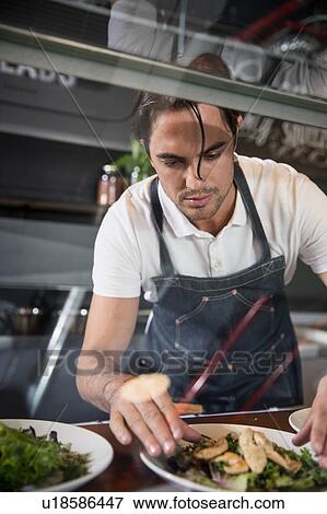 Restaurateur preparing salad behind service counter View Large Photo Image Stock Photo - Restaurateur preparing salad behind service counter. Fotosearch
