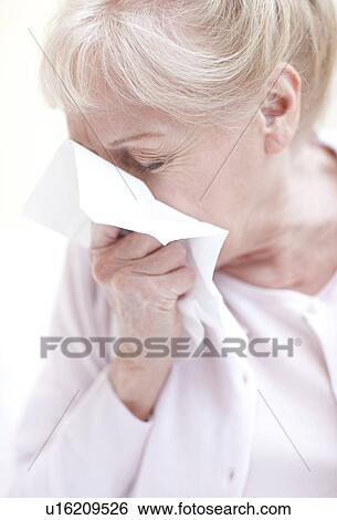 Stock Photograph - Senior woman blowing her nose. Fotosearch