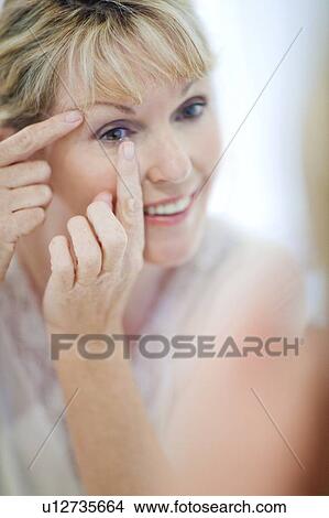 Picture - Senior woman putting in contact lenses. Fotosearch