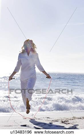 Senior woman skipping on a beach View Large Photo Image Stock Photograph - Senior woman skipping on a beach. Fotosearch