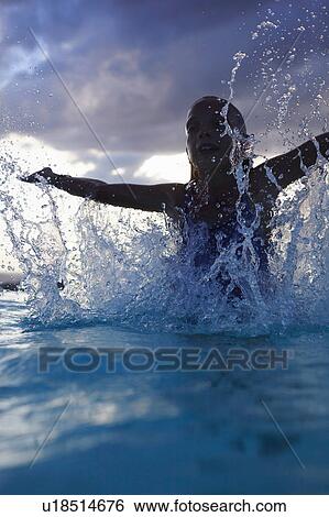 Stock Photograph - Silhouetted girl splashing in swimming pool, Buonconvento, Tuscany, Italy. Fotosearch