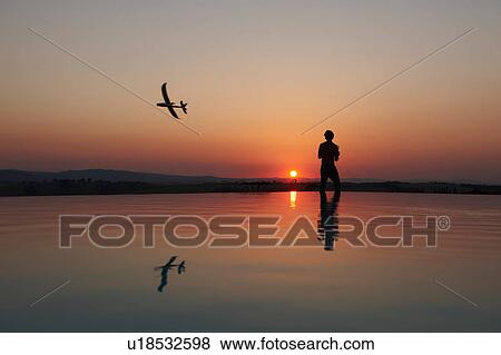 Silhouetted man flying radio controlled airplane on sunset coast, Buonconvento, Tuscany, Italy View Large Photo Image Stock Photo - Silhouetted man flying radio controlled airplane on sunset coast, Buonconvento, Tuscany, Italy. Fotosearch