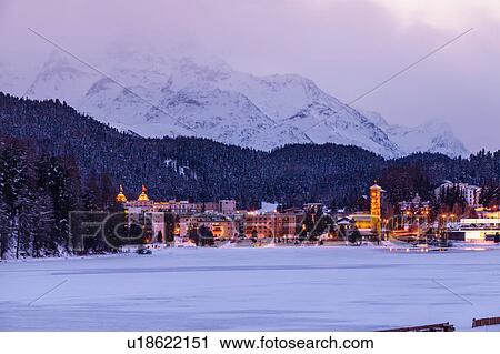 Village beneath mountain on snow covered landscape illuminated in the evening, Sankt Moritz, Switzerland View Large Photo Image Stock Image - Village beneath mountain on snow covered landscape illuminated in the evening, Sankt Moritz, Switzerland. Fotosearch