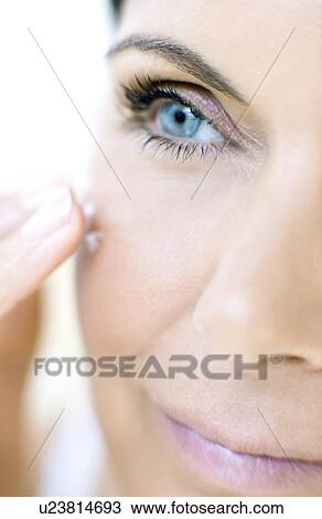 Stock Image - Woman applying face cream. Fotosearch