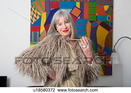 Stock Image - Woman in fur coat, abstract art in background. Fotosearch