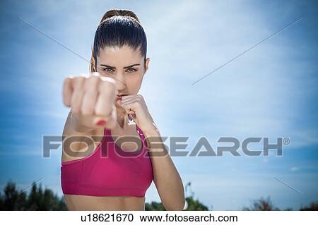 Stock Image - Woman looking at camera shadowboxing. Fotosearch