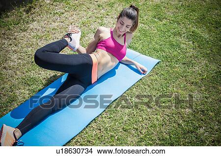 Woman on exercise mat doing leg stretching exercise View Large Photo Image Picture - Woman on exercise mat doing leg stretching exercise. Fotosearch