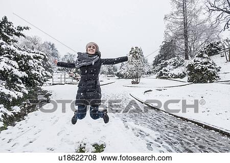 Woman on snow covered landscape arms open jumping in mid air View Large Photo Image Stock Photo - Woman on snow covered landscape arms open jumping in mid air. Fotosearch