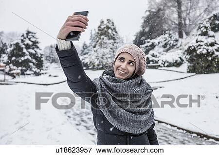 Woman on snow covered landscape using smartphone to take selfie View Large Photo Image Stock Photo - Woman on snow covered landscape using smartphone to take selfie. Fotosearch