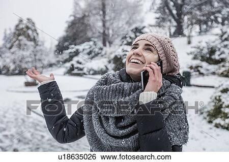 Woman on snow covered landscape using smartphone to make telephone call View Large Photo Image Stock Photograph - Woman on snow covered landscape using smartphone to make telephone call. Fotosearch