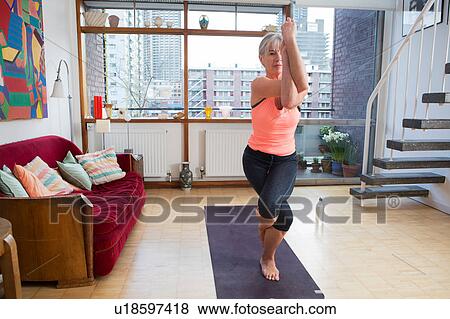 Stock Photo - Woman practising yoga at home. Fotosearch