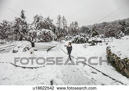 Stock Image - Woman walking on snow covered landscape. Fotosearch