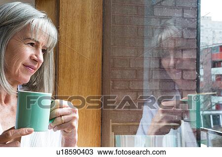 Woman with mug, looking through window View Large Photo Image Stock Image - Woman with mug, looking through window. Fotosearch