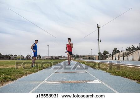 Stock Image - Young female long jumper sprint training at sport facility. Fotosearch