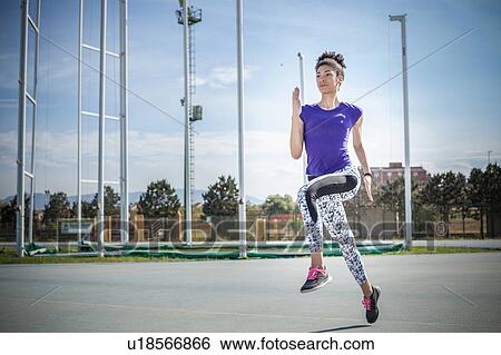 Stock Photograph - Young female sprinter sprinting at sport facility. Fotosearch