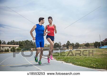 Stock Image - Young male and female runners training on running track. Fotosearch
