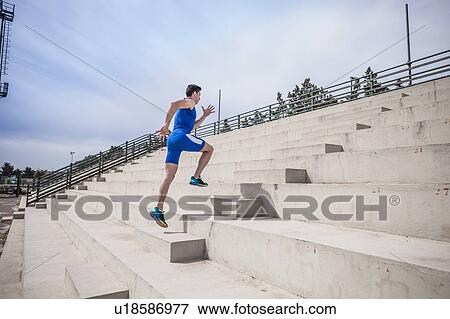 Stock Photo - Young male runner running up stairway. Fotosearch