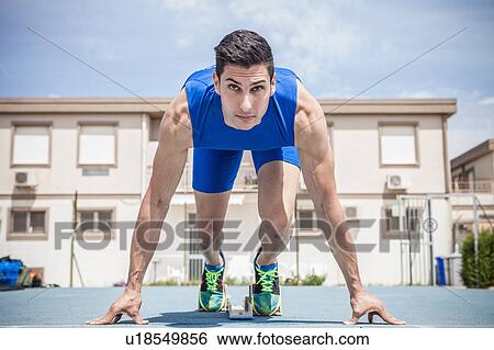Stock Photograph - Young male sprinter on his marks on running track. Fotosearch