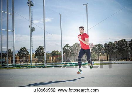 Stock Image - Young male sprinter sprinting at sport facility. Fotosearch