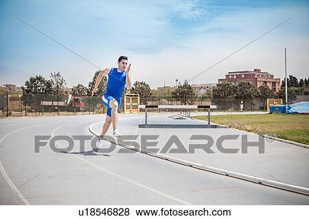 Stock Photo - Young male sprinter sprinting on running track. Fotosearch