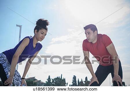Stock Photo - Young man and woman training, taking a break at sport facility. Fotosearch