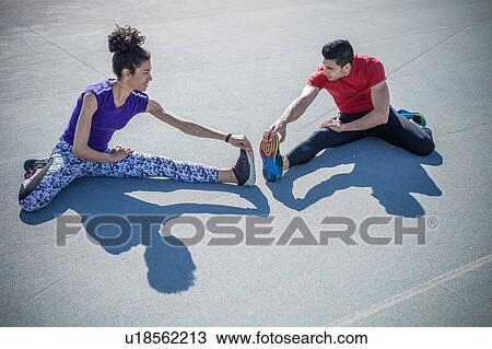 Young man and woman training, touching toes on asphalt View Large Photo Image Stock Image - Young man and woman training, touching toes on asphalt. Fotosearch