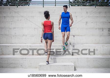 Stock Photo - Young woman and man passing on stairway whilst training. Fotosearch